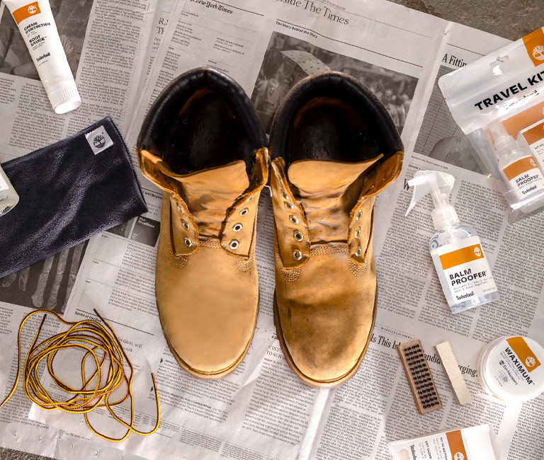 Picture of a pair of boots being cleaned with various Timberland product care items.