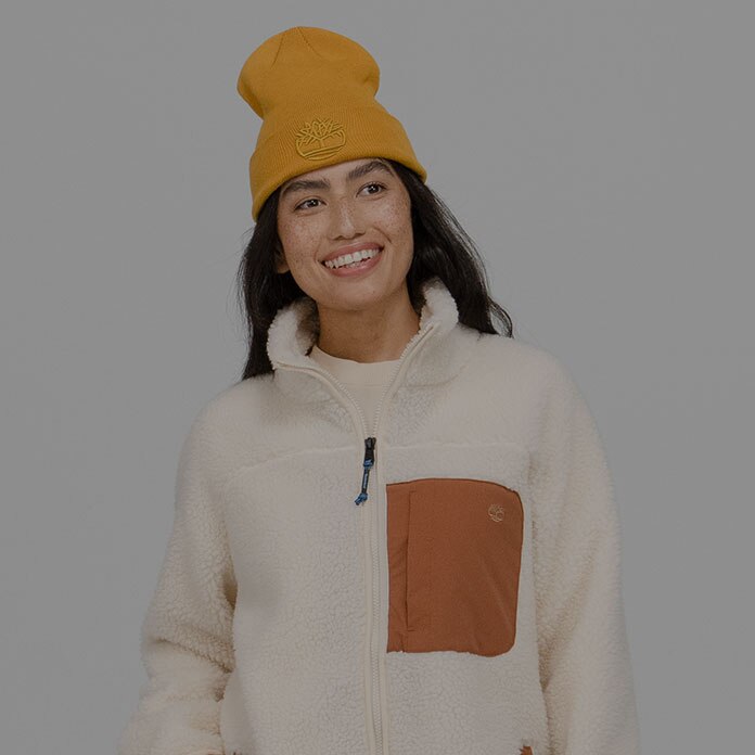 Timberland Holiday Gift Guide image of a woman wearing a light colored jacket and a yellow beanie hat