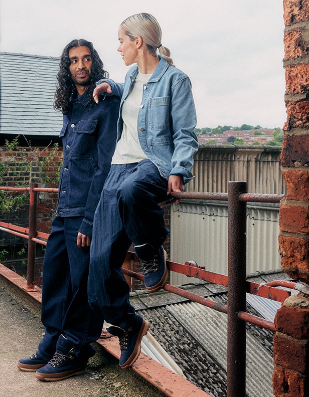 Image of a man and woman outside, both wearing dark blue boots from the Timberland Indigo Suede collection.
