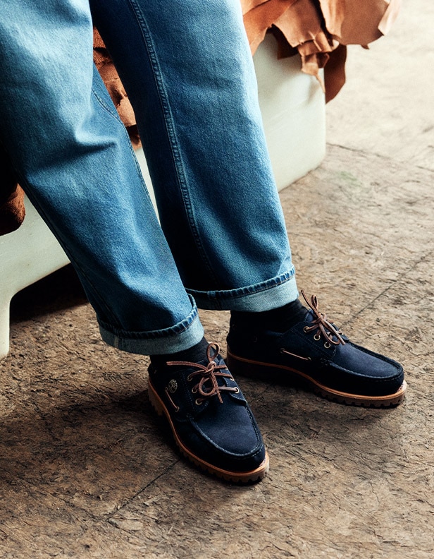 mage from just the ankle down of a person wearing jeans with the Timberland Indigo Suede Boat Shoes.