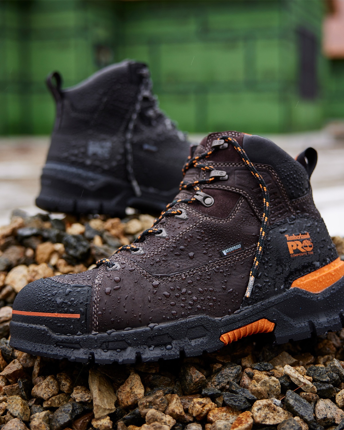 image of a pair of Timberland PRO boots with water drops sitting on a pile of rocks near water